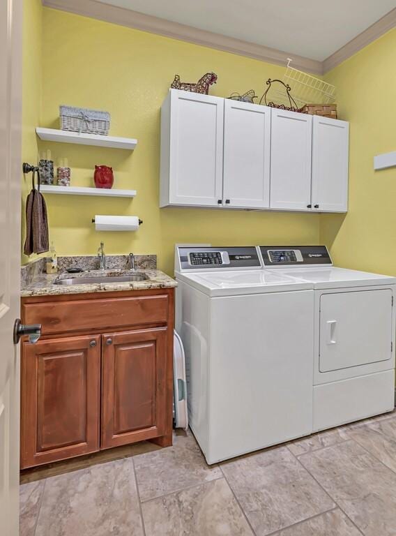 laundry area featuring cabinets, separate washer and dryer, ornamental molding, and sink