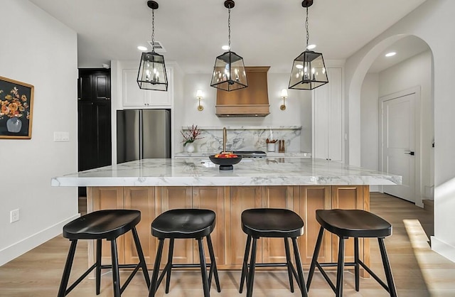 kitchen featuring light stone countertops, a kitchen breakfast bar, stainless steel refrigerator, and a large island