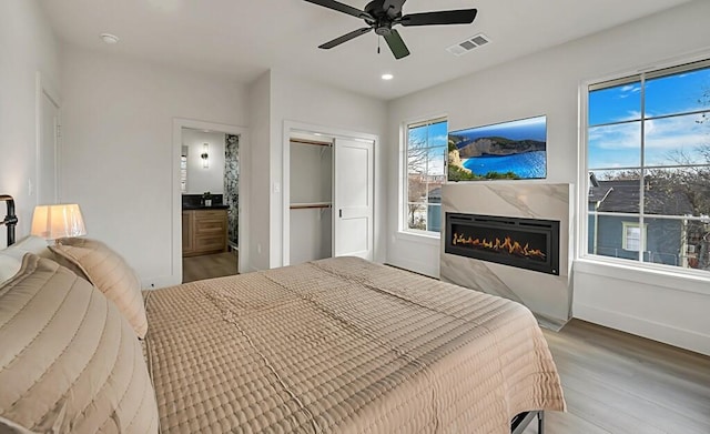 bedroom with connected bathroom, ceiling fan, a closet, and hardwood / wood-style flooring