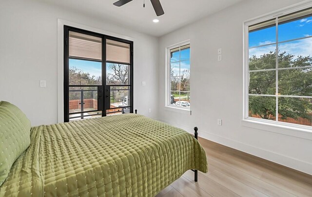 bedroom with hardwood / wood-style flooring, ceiling fan, and multiple windows