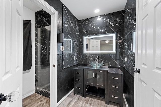 bathroom featuring vanity, hardwood / wood-style floors, tile walls, and a shower