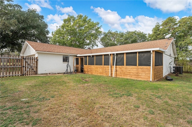 rear view of property featuring cooling unit, a yard, and a sunroom