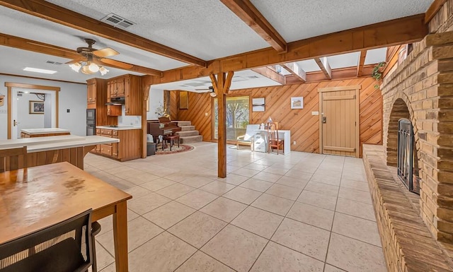 interior space with ceiling fan, light tile patterned floors, beamed ceiling, and a textured ceiling