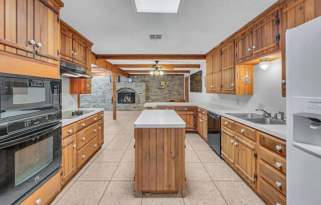 kitchen with sink, a center island, light tile patterned floors, a fireplace, and black appliances