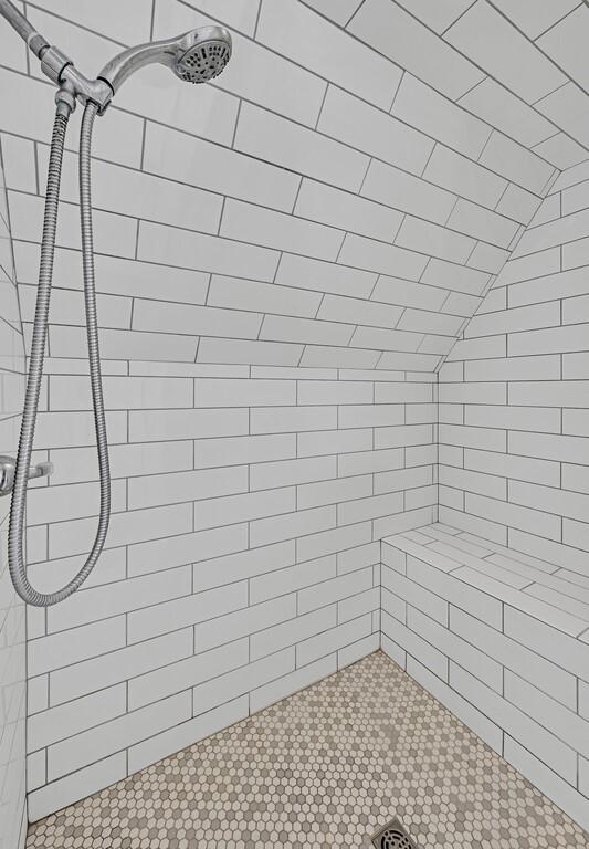 bathroom featuring tiled shower and lofted ceiling