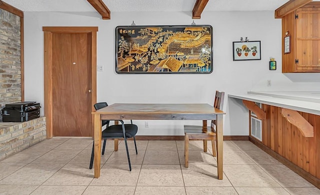 dining room with beamed ceiling, a textured ceiling, and light tile patterned flooring