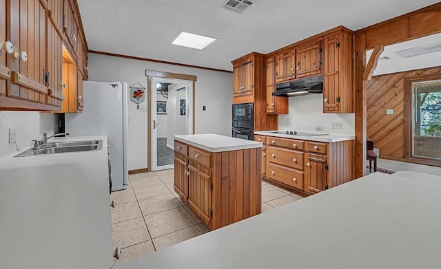 kitchen featuring sink, crown molding, a center island, black appliances, and light tile patterned flooring