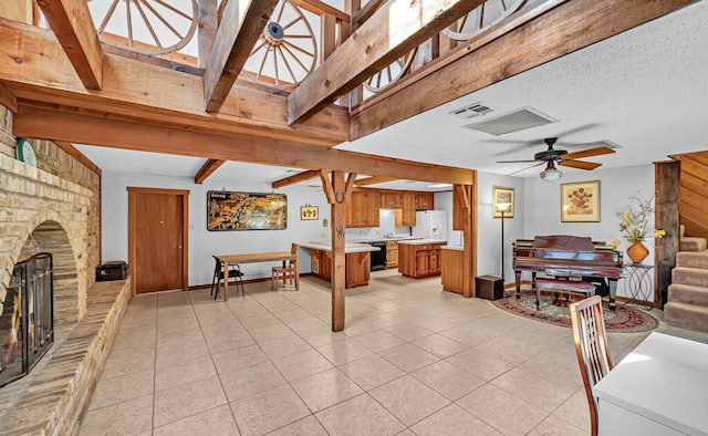 living room with ceiling fan, a large fireplace, beamed ceiling, and light tile patterned flooring