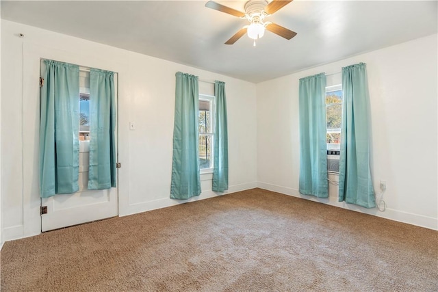 carpeted spare room with ceiling fan and plenty of natural light