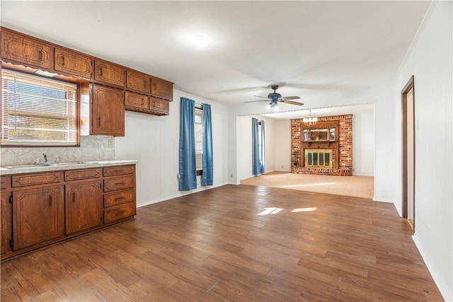 kitchen featuring a fireplace, light wood-type flooring, ceiling fan, and sink