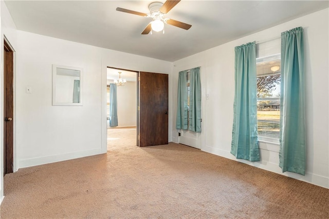 carpeted empty room with ceiling fan with notable chandelier