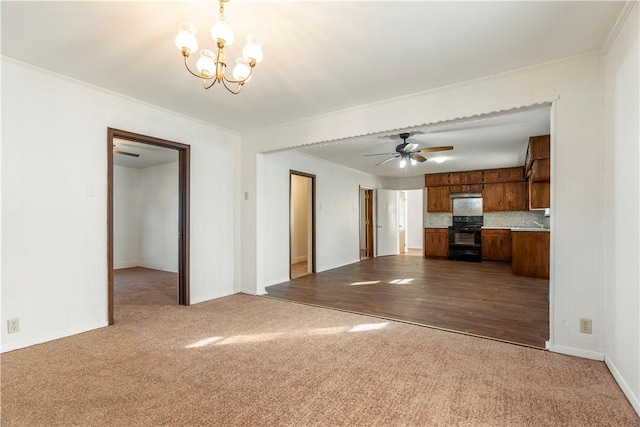 unfurnished living room with ceiling fan with notable chandelier, hardwood / wood-style flooring, and crown molding