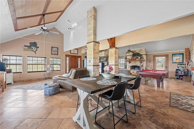 dining space with ceiling fan, a stone fireplace, billiards, and high vaulted ceiling