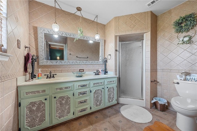 bathroom featuring tile patterned floors, vanity, tile walls, toilet, and a shower with shower door