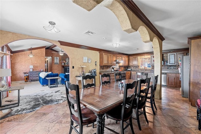 dining area with ceiling fan, ornamental molding, and sink