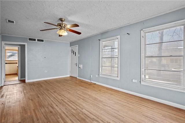 unfurnished room featuring light wood-style floors, visible vents, and a wealth of natural light