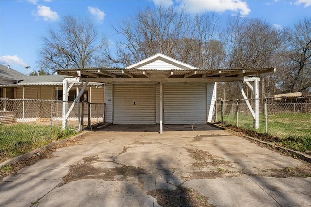 garage featuring concrete driveway and fence