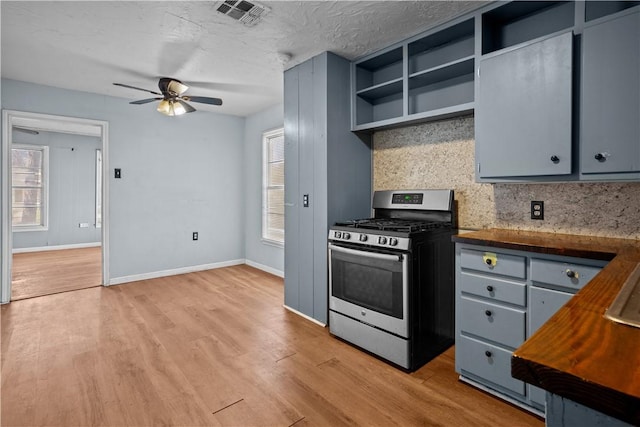 kitchen featuring open shelves, visible vents, backsplash, light wood-style floors, and stainless steel range with gas stovetop