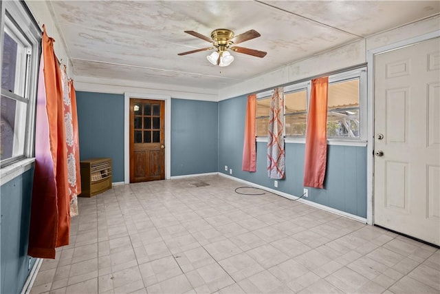 empty room with ceiling fan and baseboards