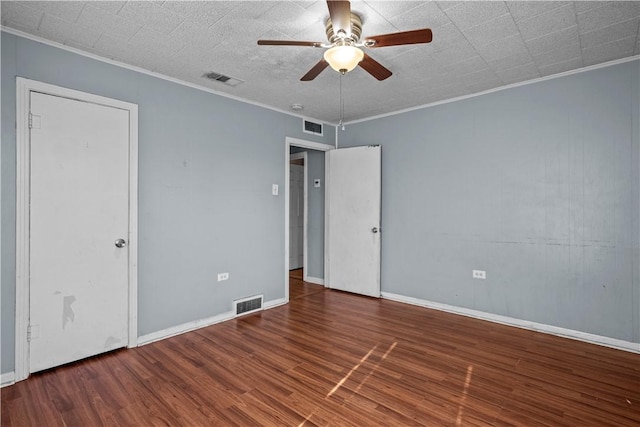 empty room featuring crown molding, visible vents, and dark wood-type flooring