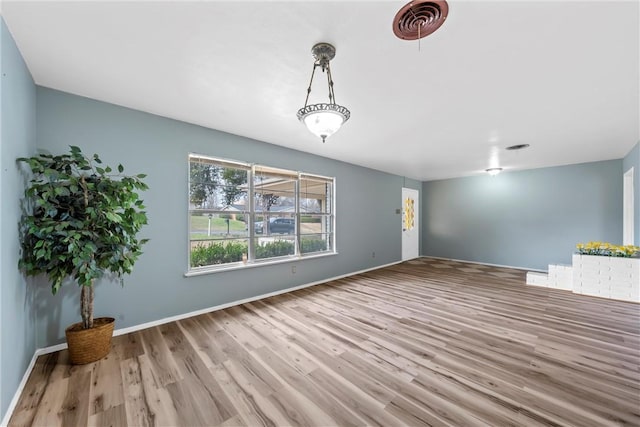 unfurnished living room featuring visible vents, baseboards, and wood finished floors