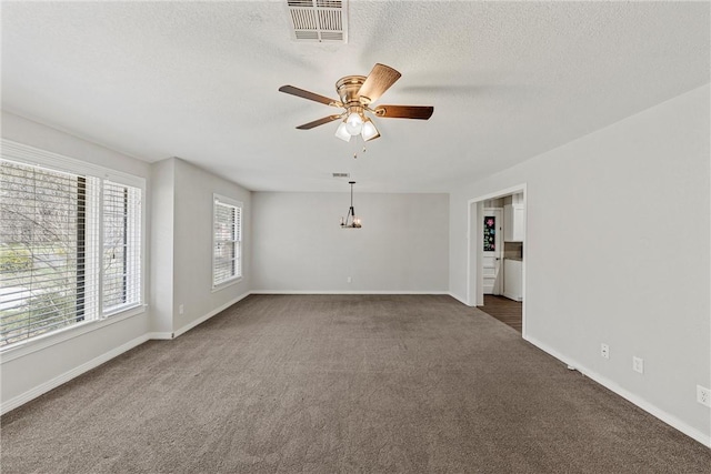 carpeted spare room with ceiling fan, a textured ceiling, visible vents, and baseboards