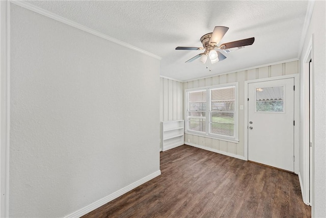 interior space with dark wood-style floors, crown molding, a textured ceiling, and baseboards