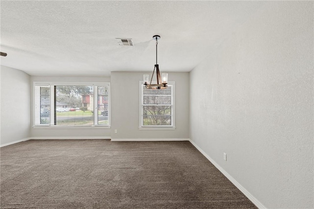 carpeted spare room with visible vents, a textured ceiling, baseboards, and an inviting chandelier