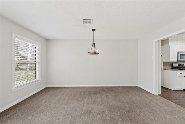 unfurnished dining area featuring baseboards, visible vents, a chandelier, and dark colored carpet