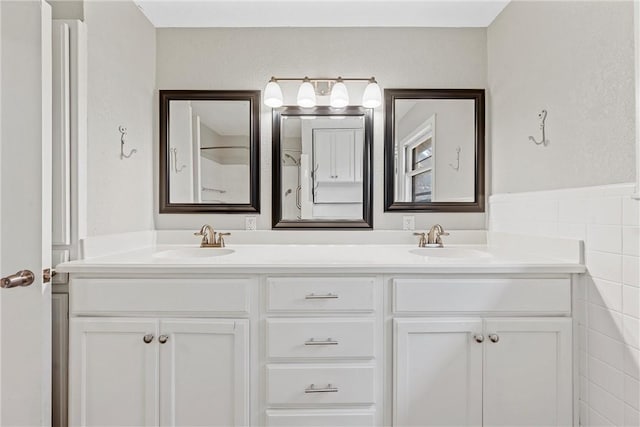 full bathroom with double vanity, tile walls, and a sink