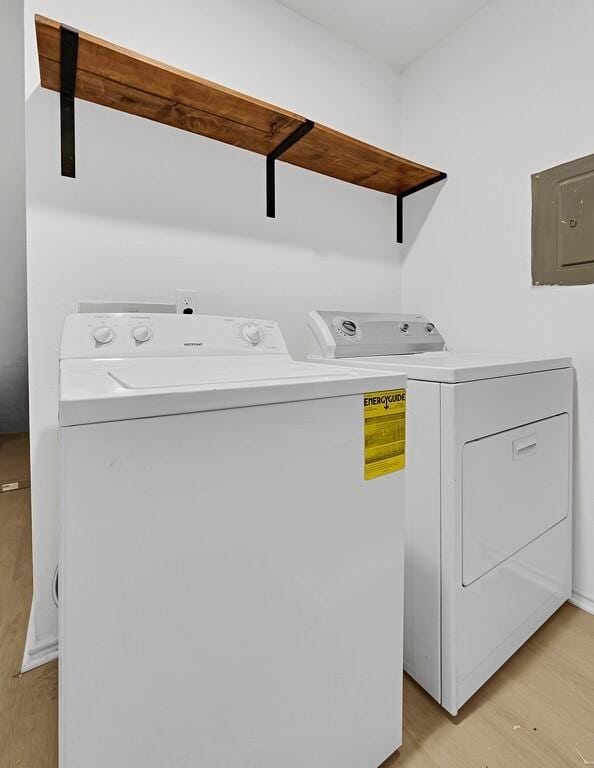 clothes washing area featuring laundry area, washer and clothes dryer, electric panel, and light wood-style floors