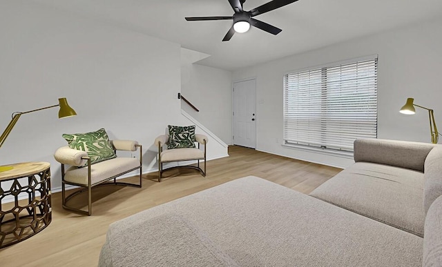 sitting room featuring stairway, ceiling fan, baseboards, and wood finished floors