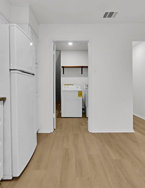 interior space featuring light wood-type flooring, baseboards, visible vents, and washing machine and clothes dryer