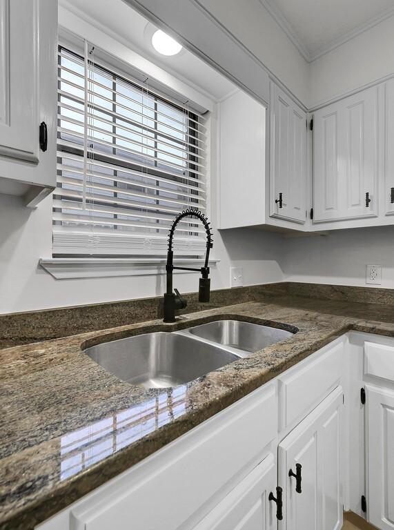 kitchen with white cabinetry, a sink, and ornamental molding