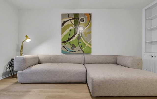 living room featuring built in shelves, wood finished floors, and baseboards