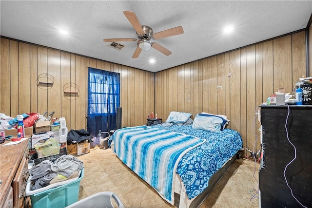 bedroom with light carpet, ceiling fan, and wooden walls