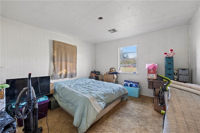 bedroom with light carpet, a textured ceiling, and wooden walls