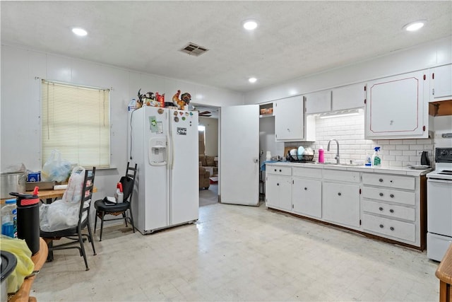 kitchen featuring white appliances, backsplash, white cabinets, sink, and a textured ceiling