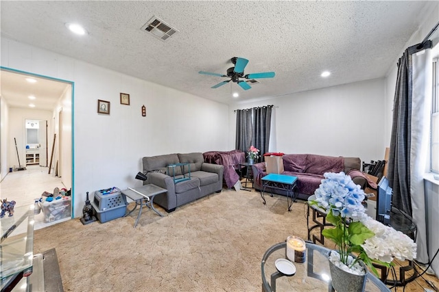 carpeted living room featuring ceiling fan and a textured ceiling