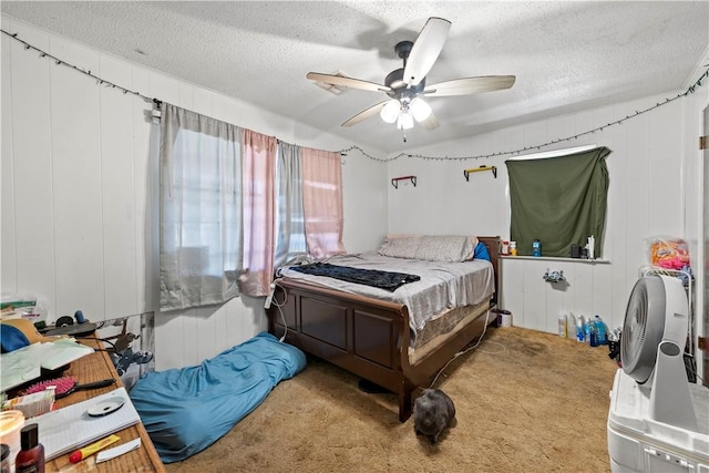 carpeted bedroom featuring ceiling fan, wood walls, and a textured ceiling