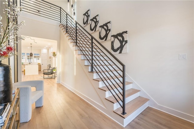 stairs with hardwood / wood-style flooring and a towering ceiling