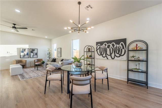 dining area featuring wood-type flooring and ceiling fan with notable chandelier