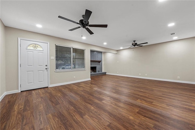 unfurnished living room with a brick fireplace, baseboards, wood finished floors, and recessed lighting