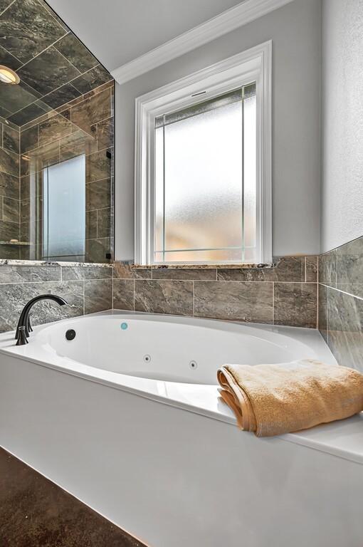 bathroom featuring crown molding and a bath