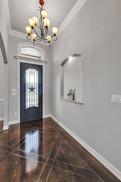 foyer entrance featuring crown molding, dark hardwood / wood-style floors, and an inviting chandelier