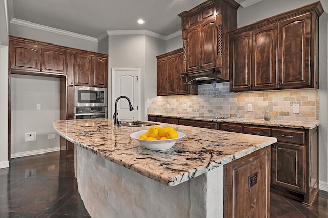 kitchen featuring sink, dark brown cabinetry, an island with sink, and appliances with stainless steel finishes