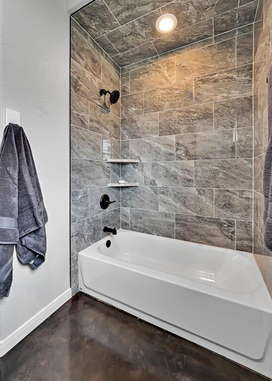 bathroom with tiled shower / bath combo and concrete floors