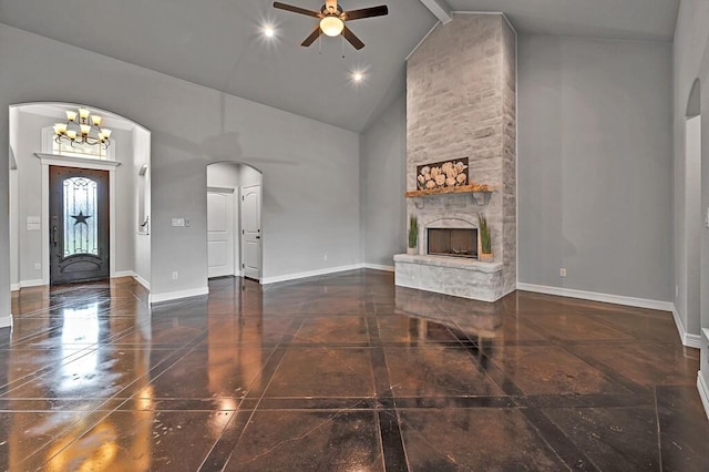 unfurnished living room featuring ceiling fan with notable chandelier, high vaulted ceiling, and a stone fireplace