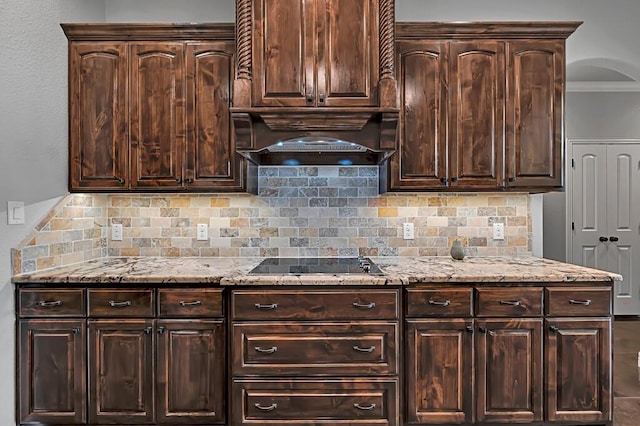 kitchen featuring decorative backsplash, black electric stovetop, light stone counters, and dark brown cabinets