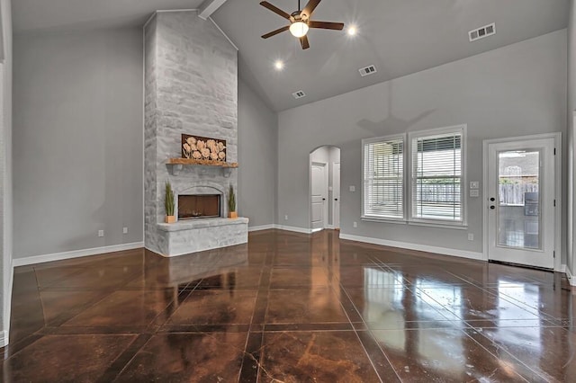 living room with beamed ceiling, ceiling fan, a stone fireplace, and high vaulted ceiling